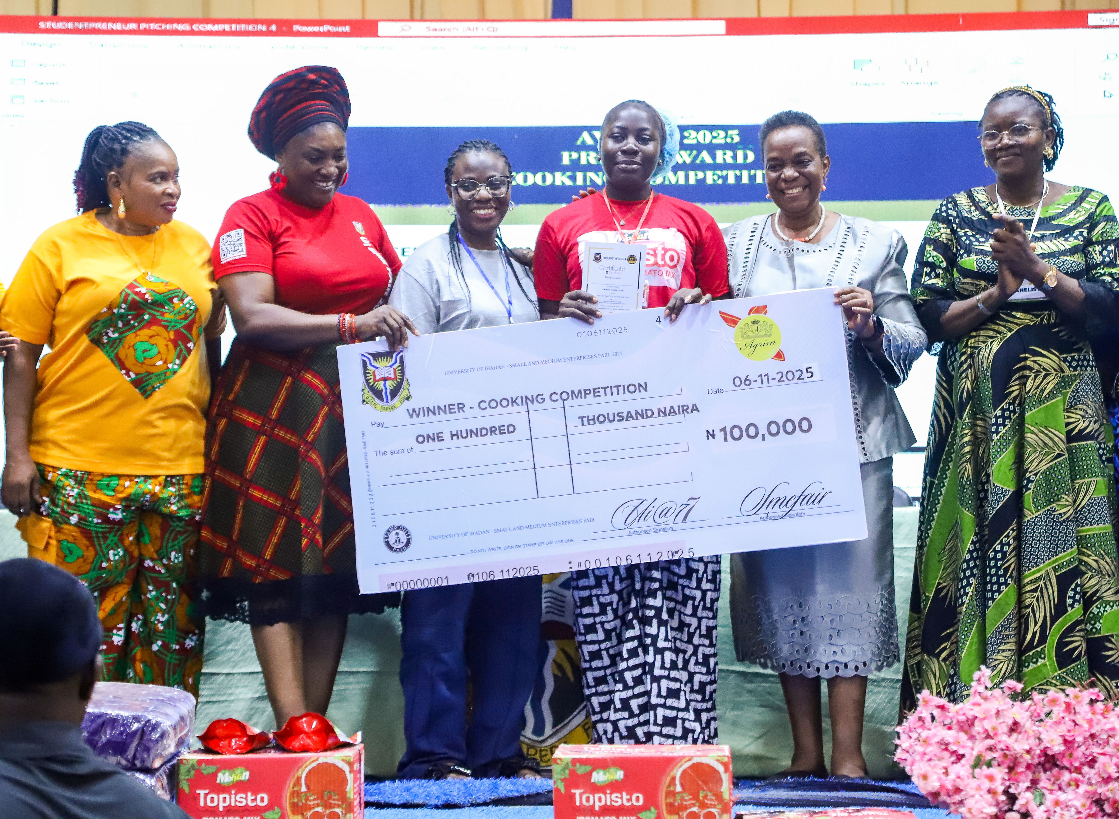Winner of the UI SME Fair cooking competition receiving a ₦100,000 prize cheque on stage at the University of Ibadan